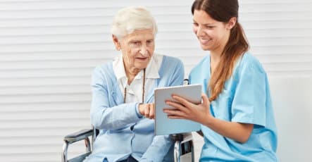 senior woman and caregiver looking at tablet